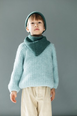 Standing portrait of a child wearing matching blue knitwear and neutral trousers — minimal kids fashion photography. 