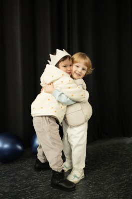 expressive children in soft pastel outfits under stage lighting — playful studio kids fashion editorial. 