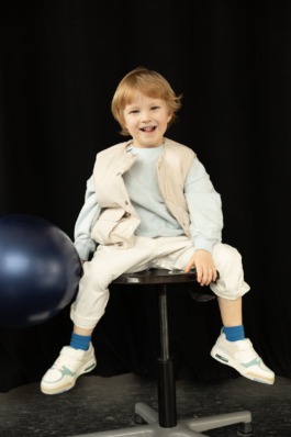 expressive children in soft pastel outfits under stage lighting — playful studio kids fashion editorial. 