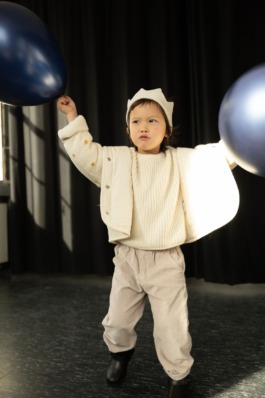 expressive children in soft pastel outfits under stage lighting — playful studio kids fashion editorial. 
