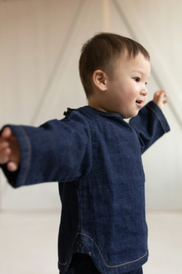 Kids fashion editorial with playful expression, clean studio colors and modern children’s styling by Berlin photographer Miriam Dang